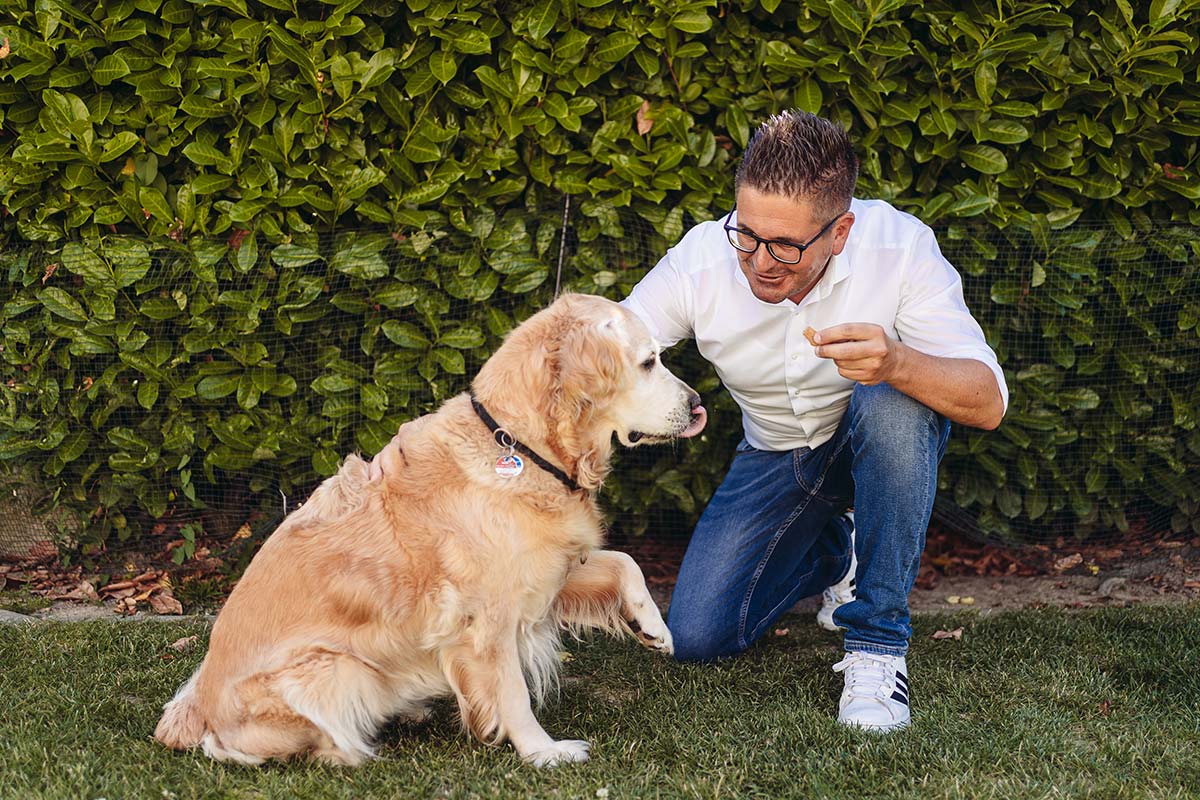 Stefan Hattenbach spielt mit einem Hund im Garten Stefan Hattenbach spielt mit einem Hund im Garten